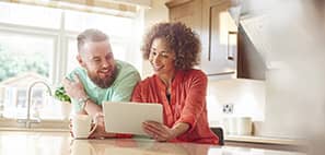 Una pareja sentada en la cocina mirando una tableta