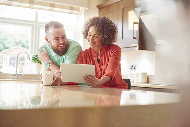 Una pareja sentada en la cocina mirando una tableta