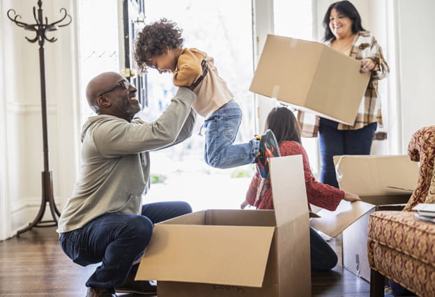 Family unpacking moving boxes in doorway of home