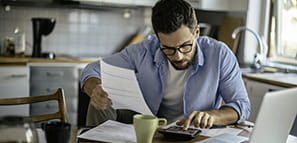 Hombre sentado en la mesa de la cocina revisando sus finanzas