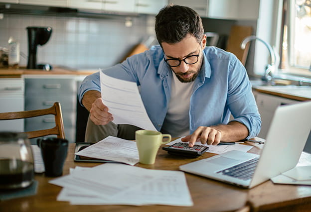 Hombre sentado en la mesa de la cocina revisando sus finanzas