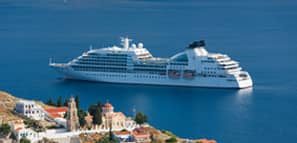 Casas en lo alto de una colina e iglesia ortodoxa griega eclipsadas por un crucero