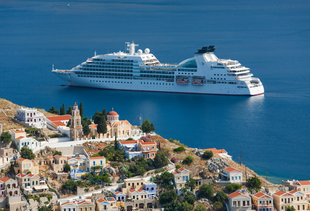 Casas en lo alto de una colina e iglesia ortodoxa griega eclipsadas por un crucero