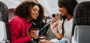 Dos mujeres toman café y conversan alegremente en un avión.