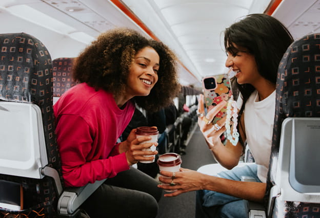 Dos mujeres toman café y conversan alegremente en un avión