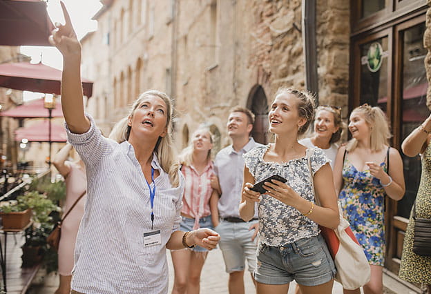 Grupo de personas paradas en una calle escuchando a un guía turístico