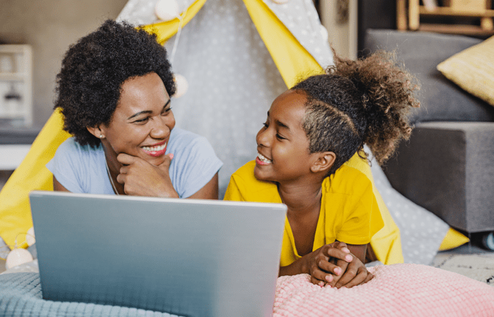 Mother and daughter smiling and looking at laptop