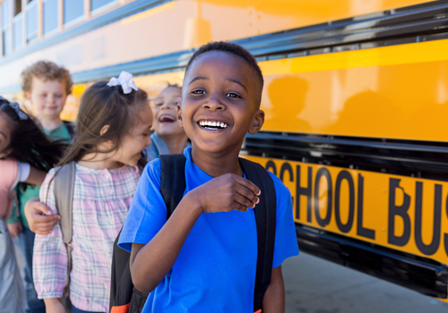 Elementary school children wait in line by the school bus