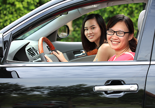 Mujer asiática feliz sonriendo sentada en el auto