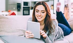 Mujer joven sentada en un sofá usando una tableta