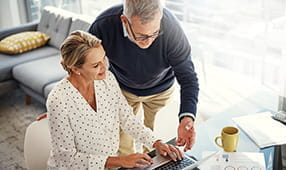 Una pareja de ancianos mirando sus finanzas en una computadora portátil