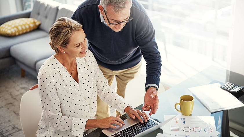 Una pareja de ancianos mirando sus finanzas en una computadora portátil