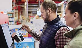 Hombre pagando con tarjeta de crédito mientras está de pie con una mujer en el supermercado
