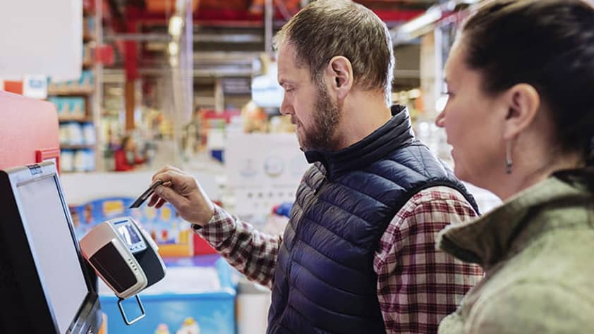 Man paying with credit card while standing with woman at supermarket