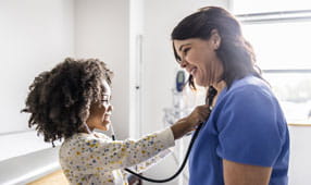 Niña escuchando el corazón de las enfermeras con estetoscopio