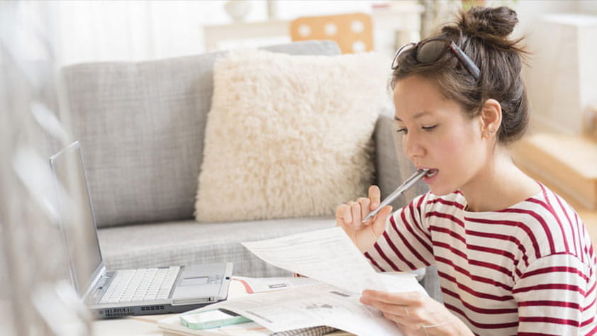 Young woman paying bills on laptop