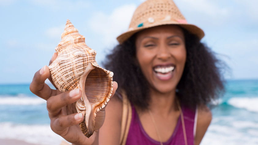 SEIU member enjoying a trip to the beach, smiling while holding a seashell
