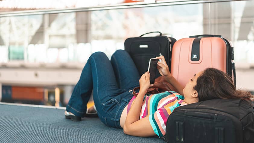 Tired tourist using luggage as a headrest while waiting at the airport