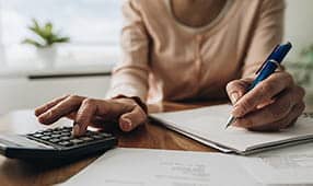 Primer plano de una mujer que planifica el presupuesto del hogar y usa la calculadora
