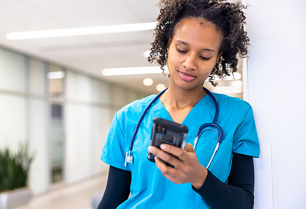 Young nurse in the hospital hallway using a smartphone 