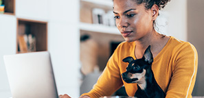 Young woman sitting with her pet dog and using laptop at home