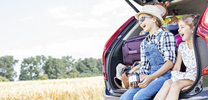 Two girls sitting in open car boot drinking tea