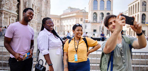 Turistas tomando fotos con guía turístico frente al Duomo en la ciudad de Milán, Italia