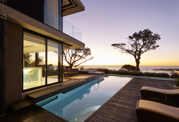 Modern luxury home showcase patio and swimming pool with sunset ocean view